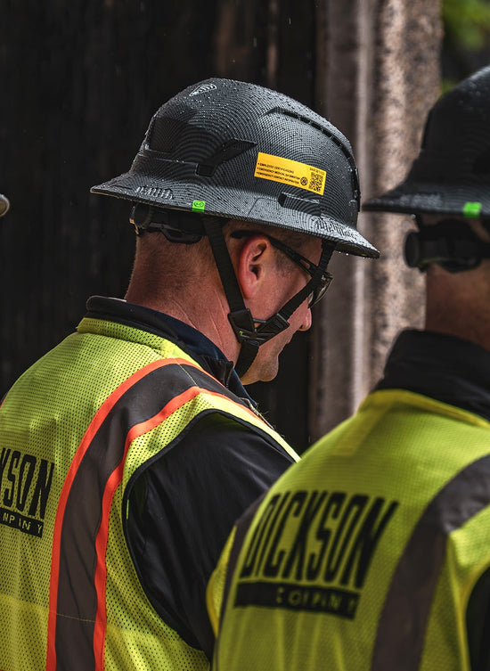 Two workers wearing high-visibility vests with 'Dickson' branding.