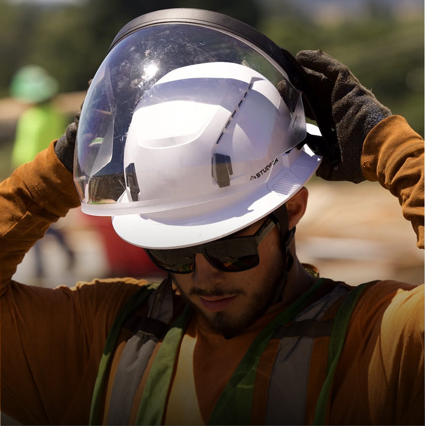 Person wearing a white hard hat and sunglasses with a blurred background