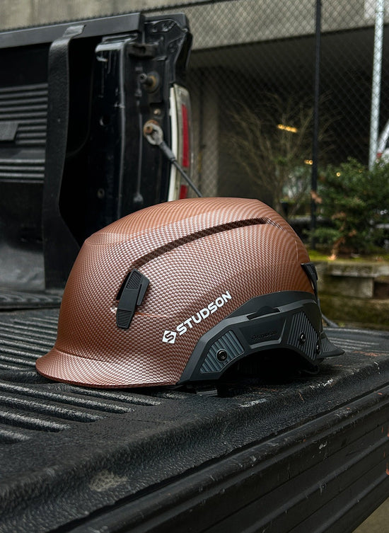 Brown hard hat with 'Studson' logo on a truck bed
