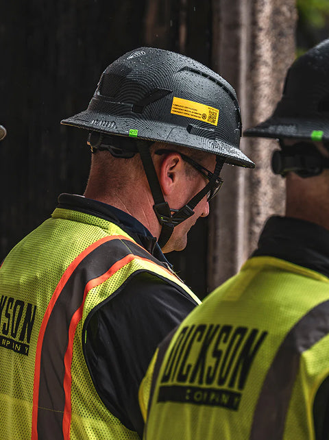 Two individuals wearing hard hats and high-visibility vests with 'Duckson' branding.