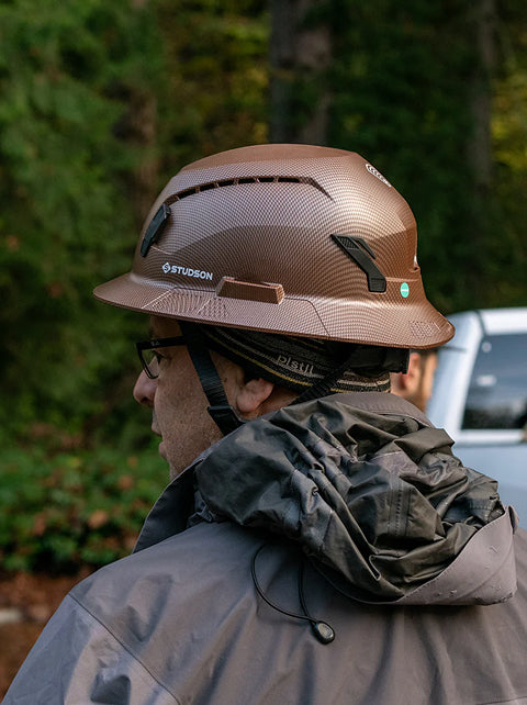 Person wearing a Stihl hard hat outdoors with blurred background